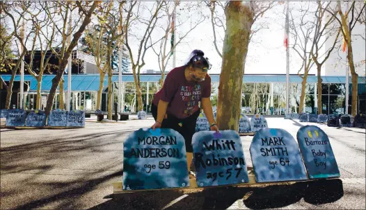  ?? RANDY VAZQUEZ — STAFF PHOTOGRAPH­ER ?? Shaunn Cartwright fixes some of the foam tombstones on display at Mcentee Plaza during a vigil in San Jose on Dec. 21.