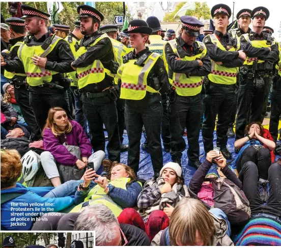  ??  ?? The thin yellow line: Protesters lie in the street under the noses of police in hi-vis jackets