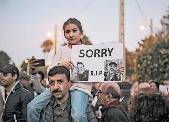  ?? MOSA'AB ELSHAMY/AP ?? A girl carries photos of Louisa Vesterager Jespersen, 24, and Maren Ueland, 28, during a candleligh­t vigil Saturday outside the Danish Embassy in Rabat, Morocco, for the Scandinavi­an students who were killed by four men in a terrorist attack in the Atlas Mountains.