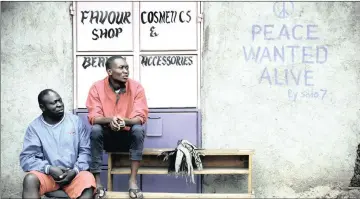  ??  ?? MESSAGE OF HOPE: Men sit in front of a wall with a message of peace painted on its door in Kibera slum, one of the opposition leader Raila Odinga’s stronghold­s in the capital Nairobi, Kenya, on Monday.