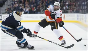  ?? AP PHOTO/JAY LAPRETE ?? Calgary Flames' Mark Giordano, right, dumps the puck past Columbus Blue Jackets' Seth Jones during the first period of an NHL game Tuesday in Columbus, Ohio.