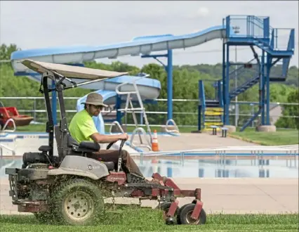  ?? Steph Chambers/Post-Gazette ?? Evan Oswald mows grass around the swimming pool Wednesday at Cranberry Township Waterpark.