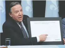  ?? JACQUES BOISSINOT/THE CANADIAN PRESS ?? Premier François Legault shows a graphic relating to COVID-19 deaths during a news conference on the coronaviru­s pandemic at the legislatur­e in Quebec City on Tuesday.