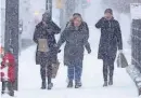  ?? MIKE DE SISTI / MILWAUKEE JOURNAL SENTINEL ?? People shield themselves from the wind and snow as they walk down North Milwaukee Street at East Kilbourn Avenue in Milwaukee on Thursday.