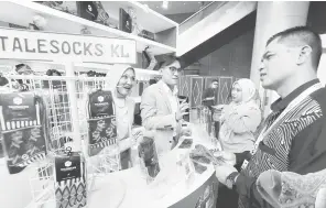  ?? — Gambar Bernama ?? UNIK: Mahu mencipta kelainan, usahawan muda Ahmad Afiz Danial (dua kiri) tampil dengan idea berbeza memperkena­lkan stoking bercorak (art socks), Talesocks, bertemakan batik dan elemen tempatan ketika melayan pelanggan di kiosknya baru baru ini.