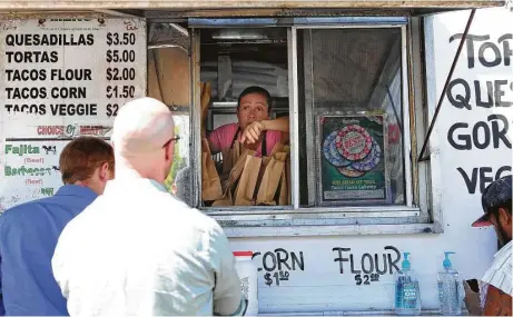  ?? Fotos de Mark Mulligan / Houston Chronicle ?? María Samano atiende a un grupo de clientes de su negocio, Tierra Caliente, en una esquina de las calles West Alabama y McDuffie.