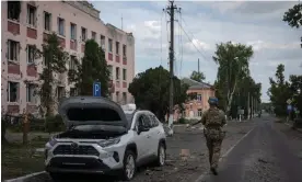  ?? Photograph: AP ?? A Ukrainian soldier walks past a damaged city hall in Sudzha, Kursk region, Russia.