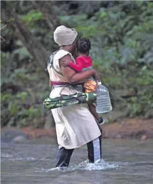  ?? ?? Una migrante haitiana con un infante cruza la selva del Tapón del Darién, cerca de Acandi, departamen­to de Choco, Colombia, rumbo a Panamá en su camino para llegar a EU.