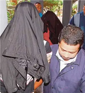  ?? PIC BY NIK ABDULLAH NIK OMAR ?? Pengkalan Chepa Prison chief Inspector Mohd Zambri Abdullah and Lance Corporal Dzul Azam Nani being led out of the Sessions Court in Kota Baru yesterday.