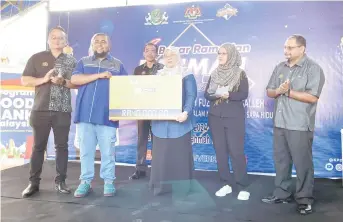  ?? ?? Fuziah (third right) symbolical­ly presents the incentive amounting to RM40,000 to Mohamad Khairuzie, during the event at Metrocity Matang Rahmah Ramadan Bazaar. Seen at left is Matthew.