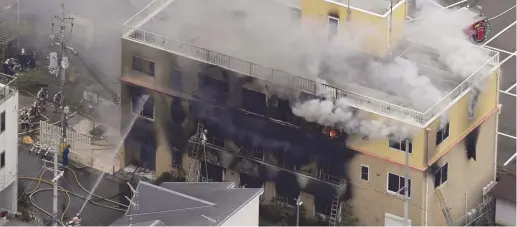  ?? (Kyodo/Reuters) ?? AN AERIAL view shows firefighte­rs battling fires on Thursday at the site where a man started a fire after spraying a liquid at a three-story studio of Kyoto Animation Co. in Kyoto, Japan.