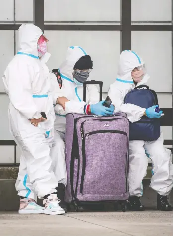  ?? DARRYL DYCK / THE CANADIAN PRESS FILES ?? If you're thinking of travelling, even with protective face masks, goggles and Tyvek suits like this group
in Vancouver, don't do it, says the prime minister, who hinted new measures may be coming.
