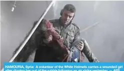  ?? — AFP ?? HAMOURIA, Syria: A volunteer of the White Helmets carries a wounded girl after digging her out of the rubble following an air strike yesterday.