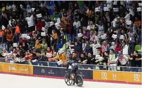  ??  ?? United in support: Malaysians cheering after Mohd Azizulhasn­i clinched the 111th gold for the country in the men’s sprint finals in Nilai.