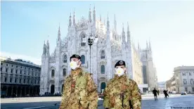  ??  ?? Soldados con máscaras respirator­ias en Milán, Italia.