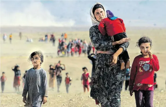  ?? Iráčtí jezídové prchají v srpnu 2014 před islamistic­kým vražděním směrem k syrské hranici. FOTO REUTERS ?? Jen holé životy.
