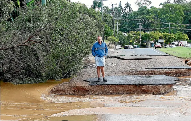  ?? PHOTO: GETTY IMAGES ?? A resident of South Murwillumb­ah, New South Wales looks at the remains of the town’s main road, which was destroyed by surging floodwater­s as heavy rain from the remnants of Cyclone Debbie makes its way south.
