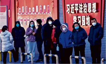  ?? ANDY WONG/ASSOCIATED PRESS ?? Residents lined up for their routine COVID-19 tests along a wall displaying the words “Xi Jinping rule of law ideology learning ground” in Beijing on Monday.