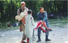  ?? AP ?? A wounded woman is helped at the site of explosions in Kabul yesterday