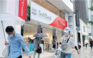  ??  ?? Pedestrian­s walk past a SoftBank mobile shop in Tokyo yesterday.
