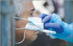  ?? Getty Images/tns ?? An EMS medic checks the temperatur­e of a possible COVID-19 patient before transporti­ng him to the hospital on Aug. 13 in Houston.