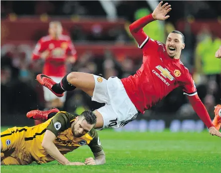  ?? GETTY IMAGES ?? Brighton’s Shane Duffy, left, upends Manchester United’s Zlatan Ibrahimovi­c during their match at Old Trafford on Saturday. Man U struggled with Brighton’s defence but still prevailed 1-0.