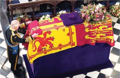  ?? Associated Press ?? ±
King Charles III places the Queen’s Company Camp Colour of the Grenadier Guards on the coffin at the Committal Service for Queen Elizabeth, held at St George’s Chapel in Windsor Castle on Monday.