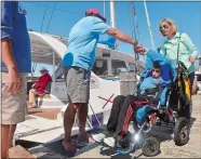 ?? SARAH GORDON/THE DAY ?? Nathan Lamb of Stonington, being pushed by his mother, Janice, fist-bumps Capt. Will Rey on Friday before setting sail on a large catamaran as part of The Impossible Dream project. The nonprofit works with Shake A Leg Miami to provide adaptive sailing...