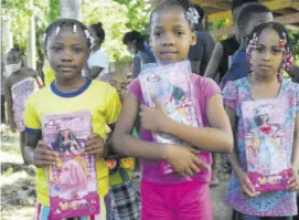  ??  ?? Three young girls display the dolls they received during Sunday’s belated Christmas treat put on by World Championsh­ips Under-20 double gold medallist Briana Williams.