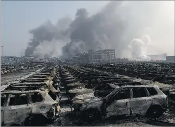  ?? — GETTY IMAGES ?? Smoke billows Thursday behind rows of burnt-out Volkswagen cars near the site of a series of explosions in Tianjin, a petrochemi­cal processing hub about 120 kilometres southeast of Beijing. The cause of the blasts remains unknown.