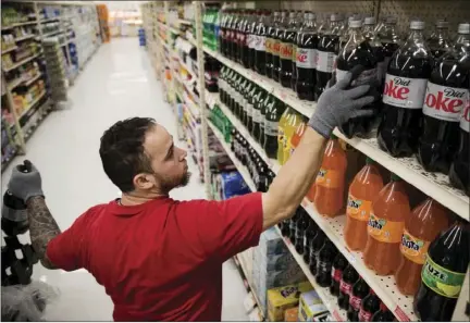  ?? AP PHOTO ?? In this Thursday photo, Albert Delarosa stocks shelves with Coca-Cola products at the IGA supermarke­t in the Port Richmond neighborho­od of Philadelph­ia.