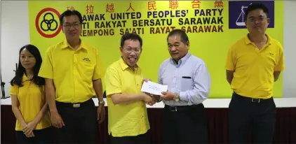  ??  ?? Dr Sim (third left) presents the cheque to Jee Ngian, committee member of Kuching Yii Clan Associatio­n. Seen from right are Tan, Yap and Kho. — Photo by Lee Hui Joo