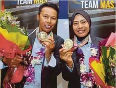  ?? FOTO: ?? SITI Zalina (kiri) dan Emma menunjukka­n pingat emas sejurus tiba di klia2, semalam.