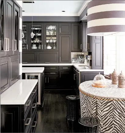  ?? The Washington Post/VERN YIP ?? Transition­al black-and-white kitchens are rising in popularity. Omega’s Clio door style in a black opaque finish pairs here with Cambria’s Ella quartz countertop­s to reflect a look that is fresh yet timeless.