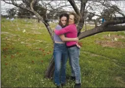  ?? ?? Anat Katz (right), a New Yorker, hugs her daughter Liat Katz on Feb. 12 as they stand among anemone wildflower­s blooming in Reim.