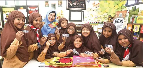  ??  ?? JUARA I LOMBA KARYA TULIS: Imawati bersama siswa SD Al Falah Darussalam membawa kata dalam aksara Jawa dan Indonesia. BOY SLAMET/JAWA POS