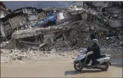  ?? UNAL CAM — THE ASSOCIATED PRESS ?? A man rides a motorbike past destroyed buildings in Antakya, southeaste­rn Turkey, on Tuesday.