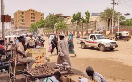  ?? — AFP file photos ?? Pedestrian­s and vehicles moving along a road outside a branch of the Central Bank of Sudan in the country’s eastern city of Gedaref.