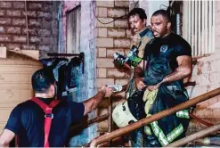  ??  ?? A firefighte­r hands his colleague a bottle of water after battling the Khaitan blaze.