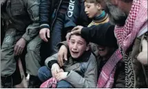  ??  ?? A Syrian boy, centre, mourns his father, who was killed by a Syrian army sniper, during a funeral in Idlib, northern Syria.