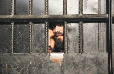  ?? Rahmat Gul / Associated Press ?? From behind bars, Taliban prisoners peeked out at media crews inside the prison in the city of Jalalabad.