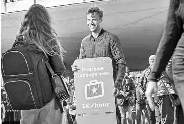  ??  ?? LuggageHer­o Founder and CEO Lawaetz, centre, holds a sign advertisin­g LuggageHer­o. Lawaetz says the concept of offering luggage storage was inspired by a trip to Barcelona and his experience­s renting his own apartment via Airbnb.