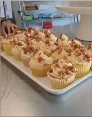  ?? Brandon Dyer ?? Corey Lance shows off maple bacon cupcakes, a favorite on the Bake and Bloom bakery’s menu.