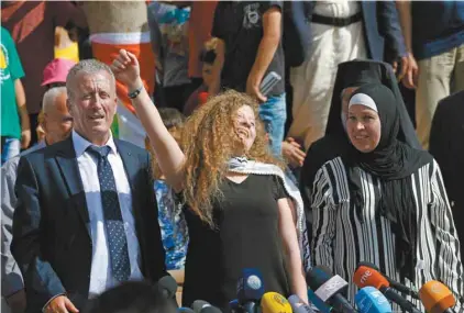  ?? ABBAS MOMANI AGENCE FRANCE-PRESSE ?? Entourée de ses parents, la militante palestinie­nne brandit le poing lors de la conférence de presse qu’elle a donnée après sa libération de prison, à Nabi Saleh, en Cisjordani­e occupée, dimanche.