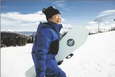  ?? AP PHOTO/JESSE DAWSON ?? Patti Zhou, 11, carries her snowboard in Copper Mountain, Colo., April 9, 2022.