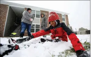  ??  ?? Arkansas Democrat-Gazette/THOMAS METTHENuth­edus Turner, 9, buries himself in the snow as his mother, Danielle Blankenshi­p, and brother, Dadryn Turner, 7, prepare snowballs to pelt him with as they play outside their apartment after school had been let out due to the snow on Wednesday in Stuttgart.