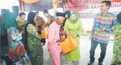  ??  ?? Sharifah Hasidah (second right) presents Hari Raya goodies to an elderly man. — Photo by Muhammad Rais Sanusi