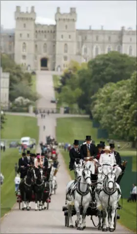  ?? PHOTOS BY ALASTAIR GRANT — THE ASSOCIATED PRESS ?? Horse-drawn carriages make their way down the Long Walk from Windsor Castle in Windsor, England, Friday. All roads seem to lead to Windsor Castle, a magnificen­t fortress perched high on a hill topped by the royal standard when the queen is in...