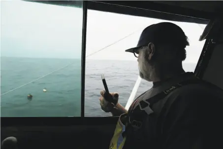  ?? Eric Risberg / Associated Press ?? Jake Bunch uses his cell phone’s GPS and new software to mark the position of an abandoned crab pot off Half Moon Bay.