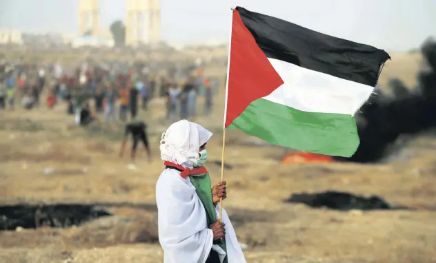  ?? S R E UT RE ?? A woman holds a Palestinia­n flag during a protest calling for lifting the Israeli blockade, Gaza, Oct. 19, 2018.